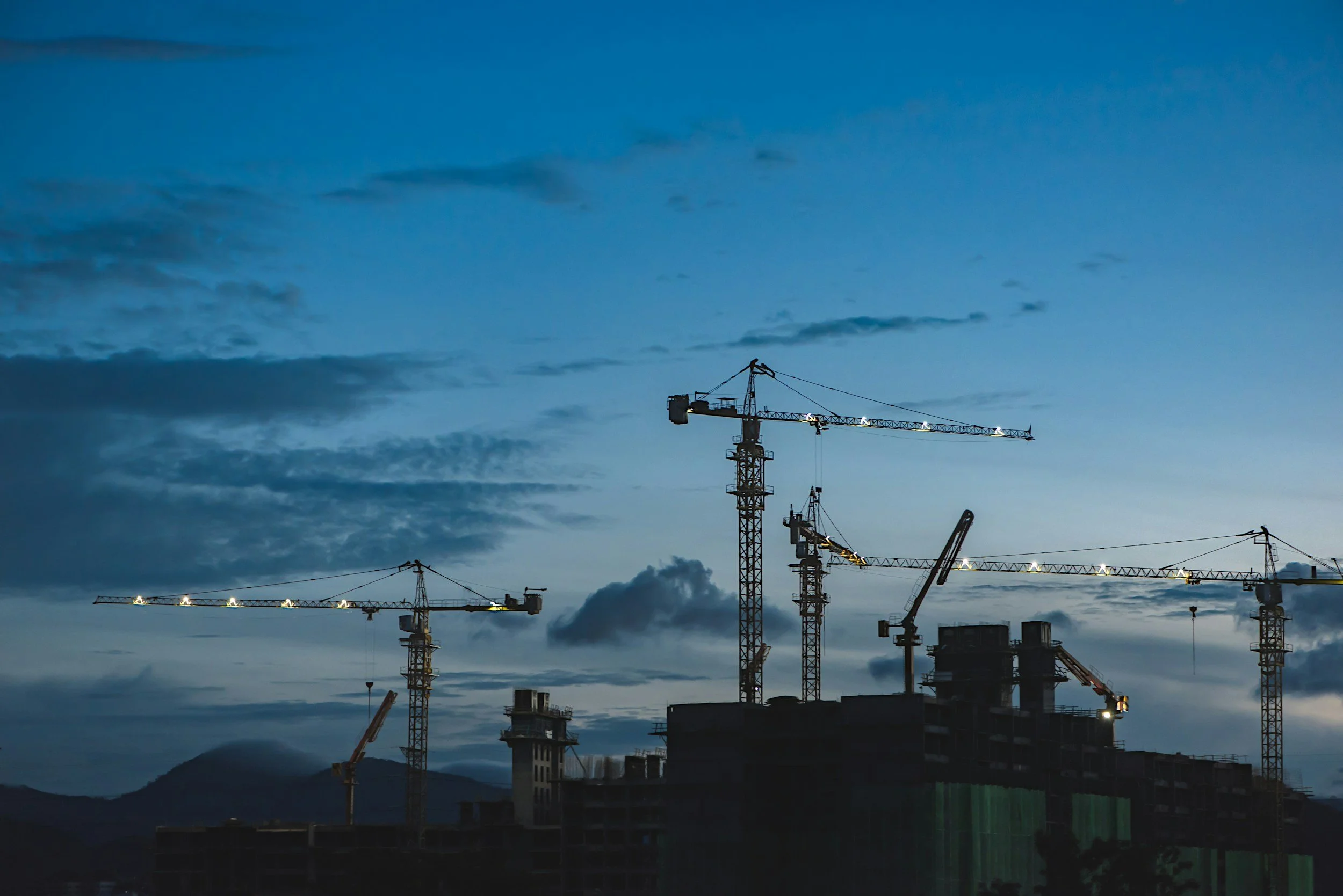 Tower cranes above a building under construction at dusk